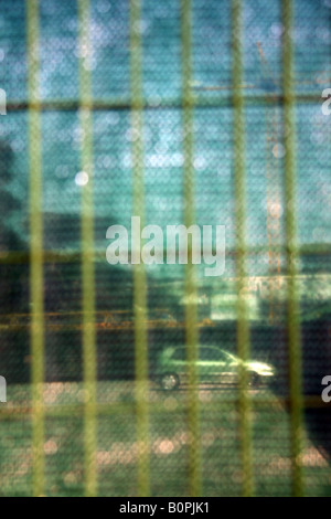 Una vettura vista attraverso la recinzione in parcheggio auto in città Foto Stock