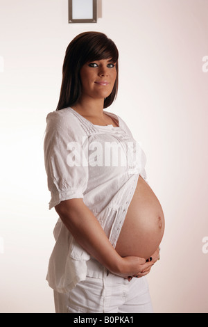 36 settimana incinta Donna adolescente tenendo il suo stomaco esposta Foto Stock