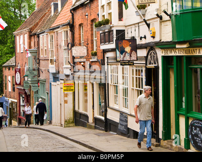 Persone in Lincoln City UK camminando sulla ripida collina passato un tradizionale pub e una sala da tè, Lincolnshire, England, Regno Unito Foto Stock