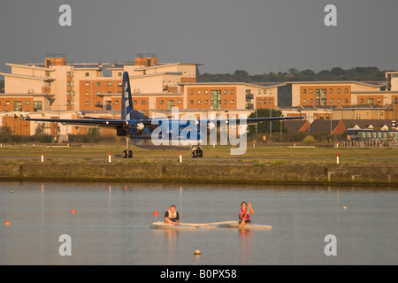 Atterraggio aereo all'Aeroporto di London City e due rematori di formazione sul Royal Albert Dock Foto Stock