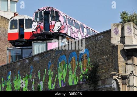 Il tubo di riciclo carrozze ferroviarie utilizzate come artisti sopra il vecchio viadotto ferroviario con pareti utilizzato per arty graffiti Foto Stock