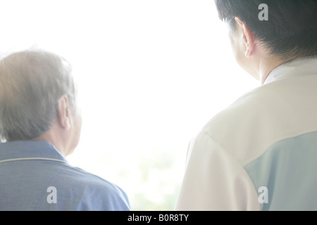 Infermiere e senior uomo rivolto verso finestra, vista posteriore Foto Stock