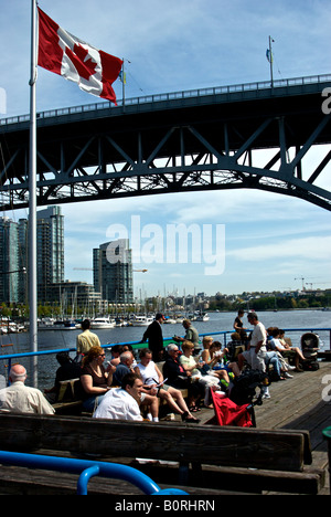 Vancouverites e turisti che si godono una soleggiata giornata calda sotto la sul grande wharf a False Creek waterfront. Foto Stock