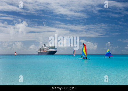 Barche a vela colorate e Holland America nave da crociera Westerdam ancorate al largo di Half Moon Cay Bahamas Foto Stock