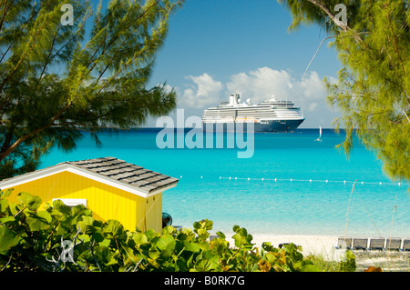 Un colorato di giallo cabana sulla spiaggia con la Holland America nave da crociera Westerdam ancorate al largo di Half Moon Cay Bahamas Foto Stock