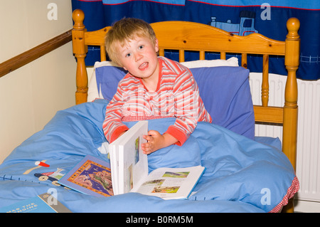 Giovane ragazzo lettura libro nel letto Foto Stock