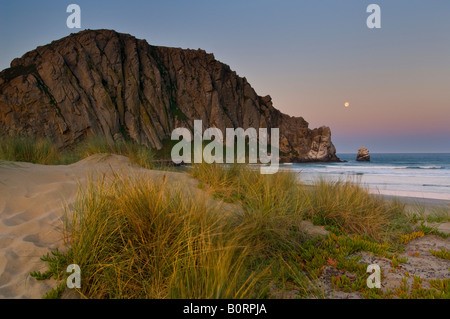 Luna piena imposta all'alba accanto a Morro Rock da dune di sabbia e al Parco di Coleman Morro Bay California Foto Stock
