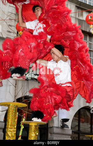 2 dragone cinese e lion dancing acrobati esecuzione di pali in cima al London Chinatown Capodanno cinese Foto Stock