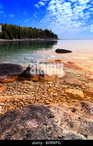 Bellissima vista su una spiaggia rocciosa con acqua chiara e riflessi dorati al tramonto Georgian Bay in Canada Foto Stock