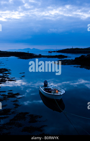 Una barca ormeggiata poggia pacificamente su calma, acque riflettente su un dusky serata nel porto Croig sull'Isle of Mull, Scotland, Regno Unito. Foto Stock