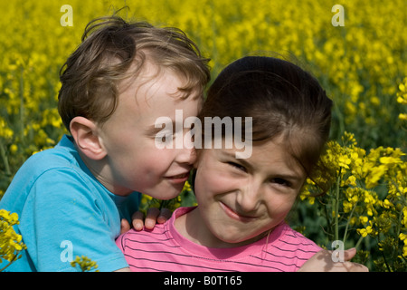 Ragazzo e ragazza scorazzare in un campo estivo Foto Stock