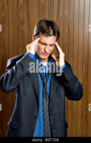 Imprenditore vivendo un mal di testa strofinando il suo tempio Foto Stock