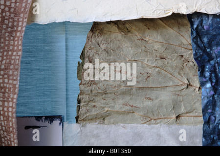 Sullo sfondo il collage con carta a trama, tessuto e una foglia secca Foto Stock