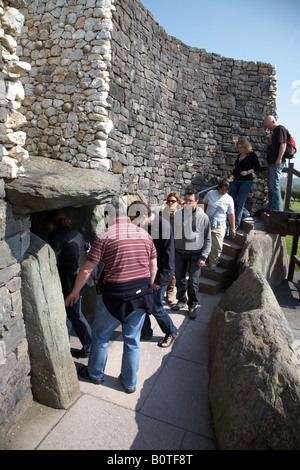 Gruppo di tour che entra nel passaggio tomba in newgrange oltre la passerella sul marciapiede che mostra la pietra di soglia e roofbox , nella contea di Meath Foto Stock