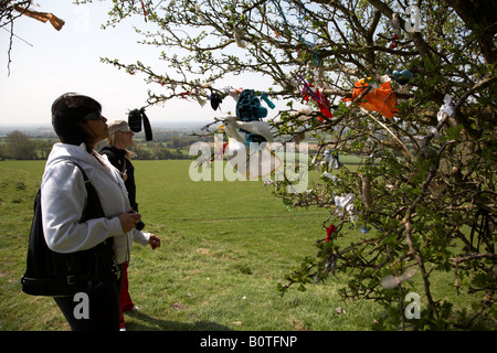 Turisti femmina fare offerte attaccato a una fata Thorn Tree sulla collina di tara nella contea di Meath, Repubblica di Irlanda Foto Stock