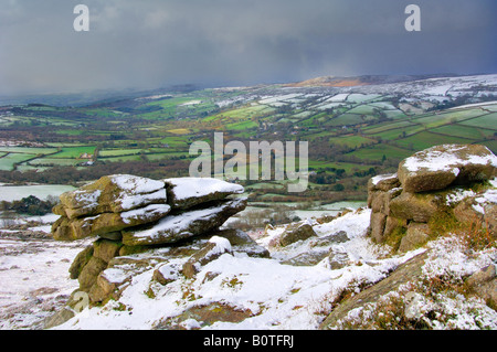 Neve pesante su Chinkwell Tor sul Parco Nazionale di Dartmoor guardando giù nel verde lussureggiante della valle Widecombe al di sotto di Foto Stock