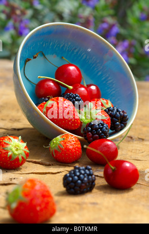 Ciotola di fresca estate raccolti di frutta morbida su una tavola di legno Tavolo da giardino, ciliegia, fragola e blackberry Foto Stock