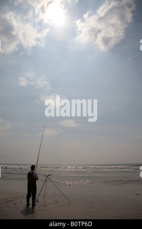 Silhouette parziale dell'uomo seafishing sotto il sole caldo e il blu cielo nuvoloso sul pollice strand beach County Kerry penisola di Dingle Foto Stock