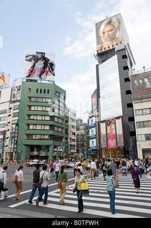 Pedoni che attraversano via sotto i cartelloni pubblicitari di prodotti di moda in elegante quartiere di Omotesando a Tokyo Giappone Foto Stock