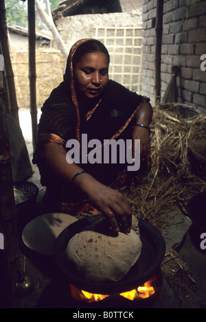 Una donna per la cottura di un pane naan nella sua casa di Bangladesh Foto Stock