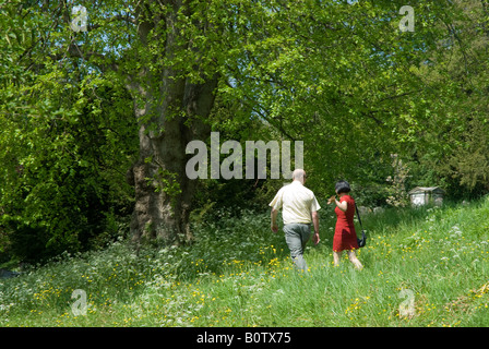 Giovane a piedi in erba lunga e fiori selvatici. Un abbigliamento informale e vestito rosso Foto Stock