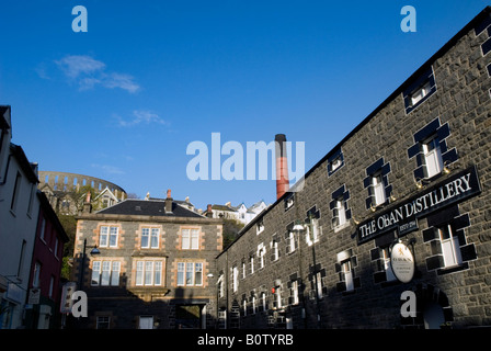 Oban Distillery con McCaig's Tower in background, Oban, Scozia Foto Stock