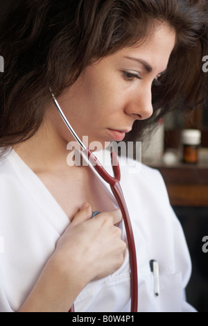Giovane donna medico ascoltando il proprio cuore con uno stetoscopio Foto Stock