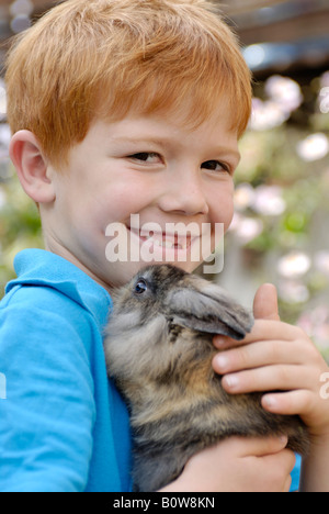 Little Boy tenendo un Coniglio europeo (oryctolagus cuniculus) Foto Stock