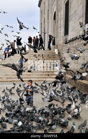 Ragazzo a caccia di piccioni davanti ad una moschea di Istanbul, Turchia Foto Stock