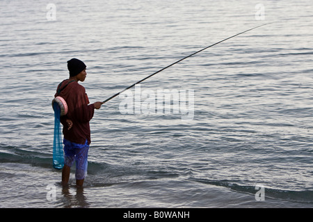 Fisherman pesca sotto la pioggia sulla riva dell'Isola di Lombok, Lesser Sunda Islands, Indonesia Foto Stock