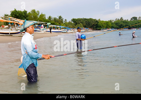 Vecchio Pescatore in piedi in mare nei pressi di Senggigi angling per piccoli pesci utilizzando i metodi tradizionali, Isola di Lombok, Lesser Sunda ho Foto Stock