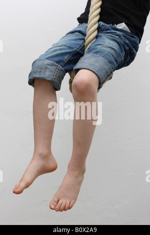 Un bambino seduto su una corda swing Foto Stock