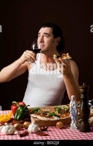 Stereotipato uomo italiano tenendo un bicchiere di vino e mangiare la pizza Foto Stock