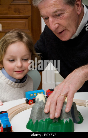 Un nonno e nipote giocare con un giocattolo di treno Foto Stock