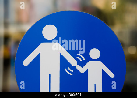 Una traversata di segno che indica che gli adulti devono tenere un bambino la mano Foto Stock