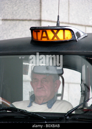 Vecchio nero Inglese taxi illuminato con figure - driver di attesa per passeggero, Inghilterra, Birmingham Foto Stock