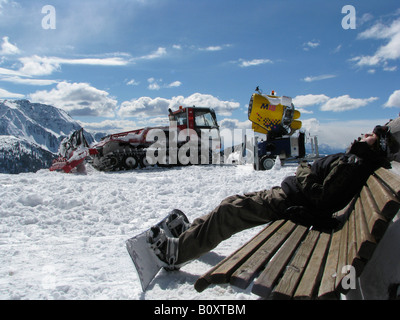 Gatto delle Nevi e la neve canon, giovane donna con lo snowboard si rilassa su banco, Italia, Suedtirol, Sarentino, Reinswald Foto Stock