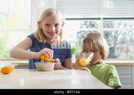 Un ragazzo e una ragazza (8-9) preparare il succo d'arancia fresco, ritratto Foto Stock