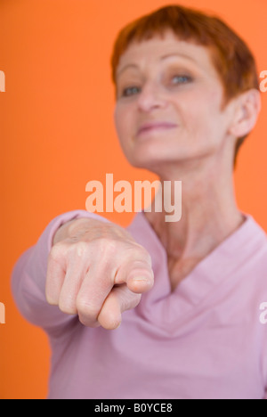 Felice donna più anziana, puntando con il dito per la fotocamera Foto Stock