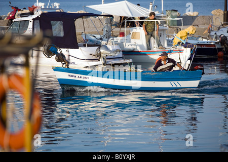 Piccola barca da pesca di lasciare il porto la sera presto Faliraki Rodi Grecia Foto Stock