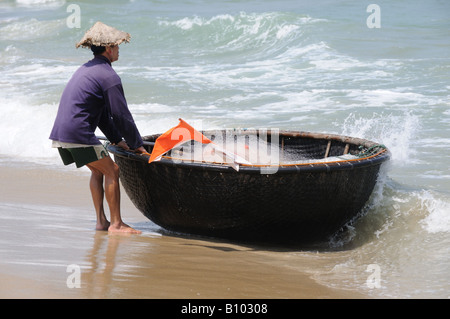 Pescatore con coracolo tradizionale vietnamita o barca a cesto tessuta da bambù Cua dai Beach Vietnam Foto Stock