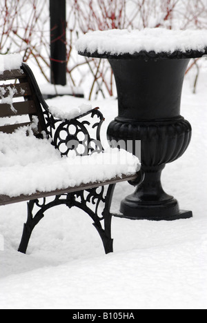 Coperta di neve da banco e vaso vuoto in winter park Foto Stock