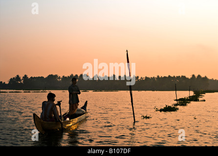 INDIA Kerala due pescatori indiani a remi in legno la loro barca nel Lago Vembanad al tramonto come partirono per trascorrere la notte di pesca Foto Stock