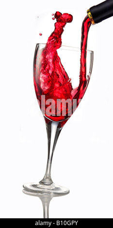 Il vino rosso è versata in un bicchiere contro uno sfondo bianco Foto Stock