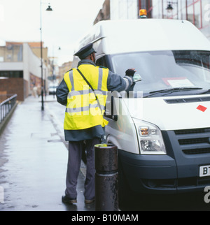 Il guardiano del traffico mette un biglietto buono di parcheggio su un furgone bianco parcheggiato vicino alla tenuta del Barbican in Whitecross Street, Londra Inghilterra UK KATHY DEWITT Foto Stock