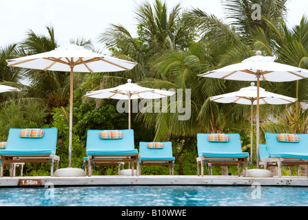 Sedie a sdraio che si affaccia sulla piscina infinity e laguna a Anantara resort nelle Maldive Foto Stock