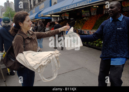 Volontari nella parte anteriore del fairway supermercato in New York dare via riutilizzabile sacchi di tela per gli amanti dello shopping per sostituire i sacchetti di plastica Foto Stock