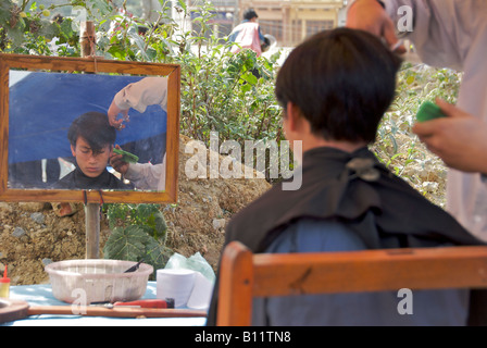 Ragazzo avente taglio capelli Bac Ha mercato domenicale nel Vietnam del Nord Foto Stock