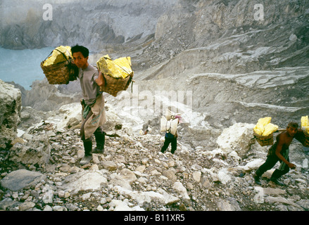 I minatori portano ceste piene di zolfo fuori del vulcano al punto di raccolta. Foto Stock