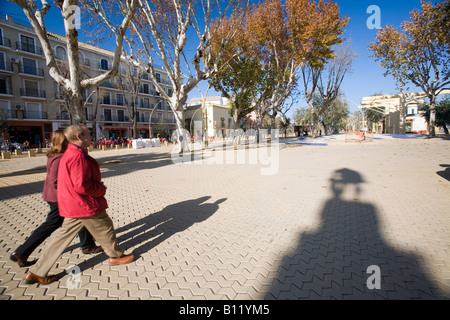 Un giovane a piedi dall'ombra di una statua in Alameda de Hercules square, Siviglia, Spagna Foto Stock